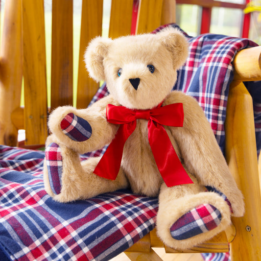 15-inch tan plush bear with red bow and plaid paw pads sitting on red, white, and blue plaid fabric.
