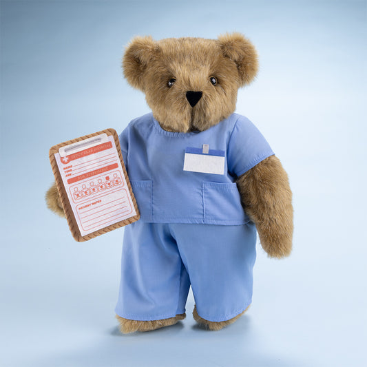 Honey-colored plush bear wearing light blue nurse scrubs holding a medical chart with a pocket badge on the shirt.