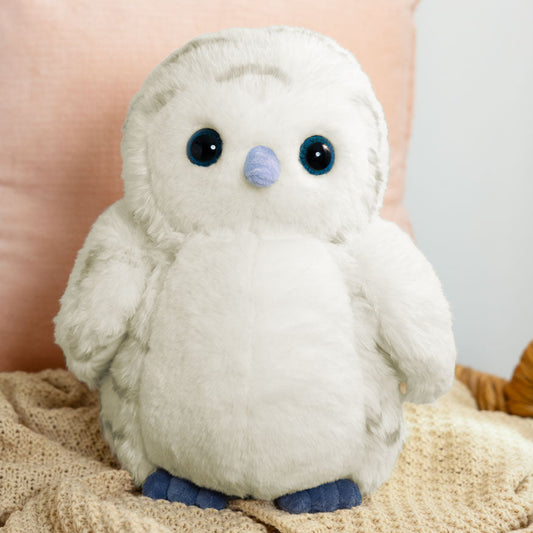 Soft white snowy owl plush with black eyes and blue beak and feet on a knitted blanket.