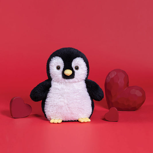 Plush penguin toy with red hearts on a red background