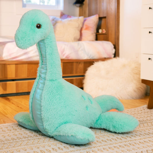 Large turquoise plush dinosaur with long neck lying on a patterned rug in a bedroom setting.