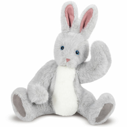 Gray and white plush bunny with pink inner ears and blue eyes sitting with one paw raised.