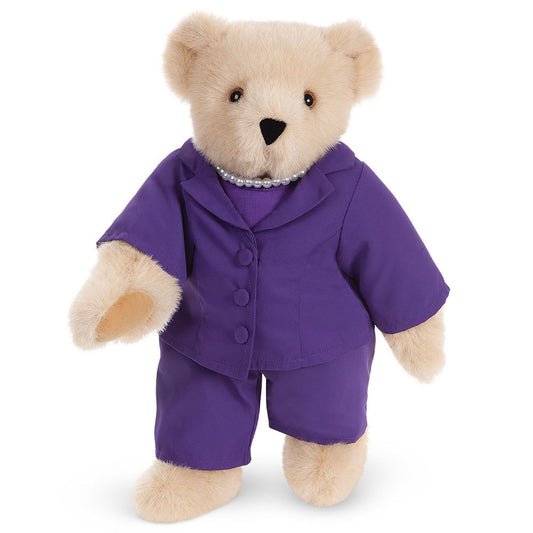 Honey-colored 15-inch teddy bear wearing a tailored purple business suit with a pearl necklace and brown eyes.